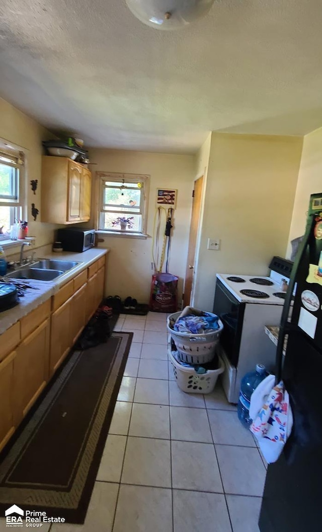 kitchen featuring light tile patterned flooring, electric stove, a healthy amount of sunlight, and sink