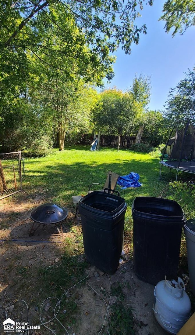 view of yard featuring a trampoline and a fire pit