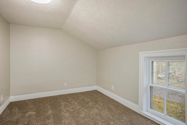 carpeted spare room featuring lofted ceiling and a textured ceiling