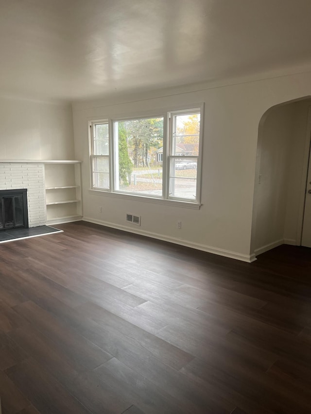 1060 Cross St, Saginaw, MI 48602 - unfurnished living room with arched walkways, dark wood-style floors, baseboards, and a fireplace