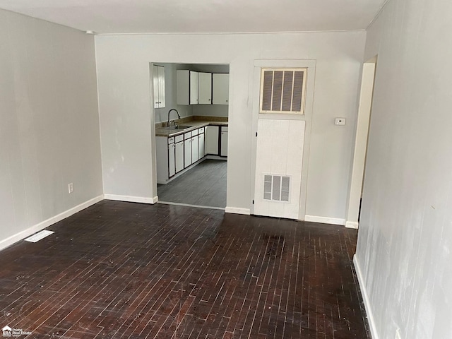 1063 Dunkirk Ave, Mount Morris, MI 48458 - empty room featuring dark wood-style floors, a sink, and baseboards