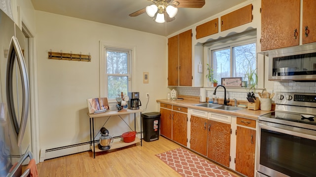 kitchen with sink, decorative backsplash, ceiling fan, light wood-type flooring, and stainless steel appliances