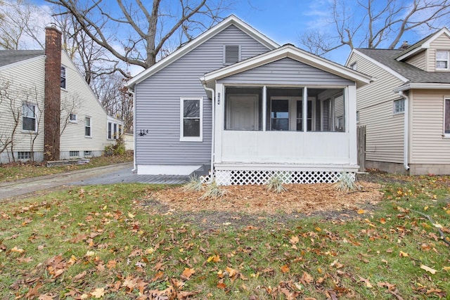 bungalow-style house featuring a sunroom and a front lawn