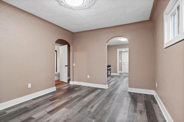 empty room featuring a textured ceiling and dark hardwood / wood-style floors