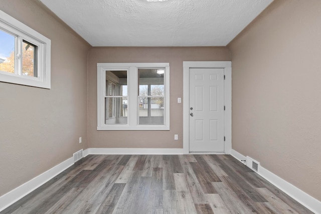 unfurnished room with dark hardwood / wood-style flooring and a textured ceiling