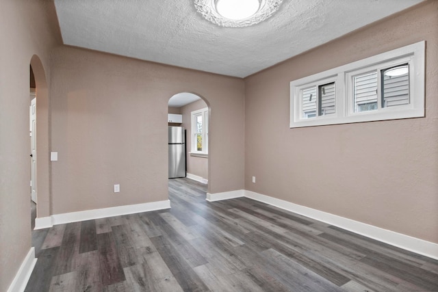 empty room featuring a textured ceiling and dark wood-type flooring