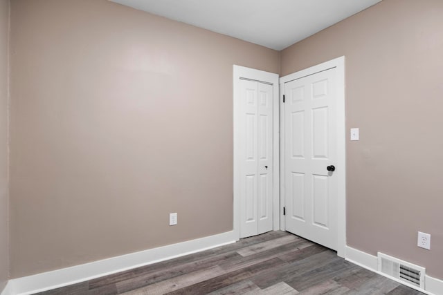 unfurnished bedroom with a closet and dark hardwood / wood-style flooring