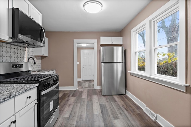 kitchen featuring white cabinets, hardwood / wood-style flooring, backsplash, and appliances with stainless steel finishes