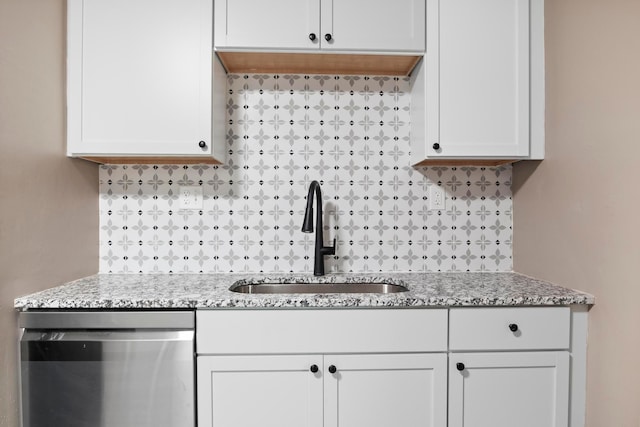 kitchen featuring backsplash, white cabinetry, sink, and stainless steel dishwasher