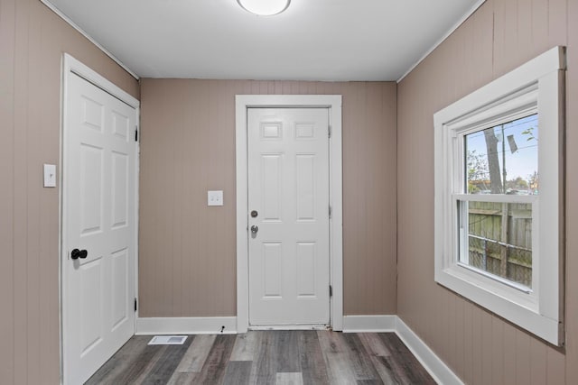 doorway with wood walls and dark wood-type flooring