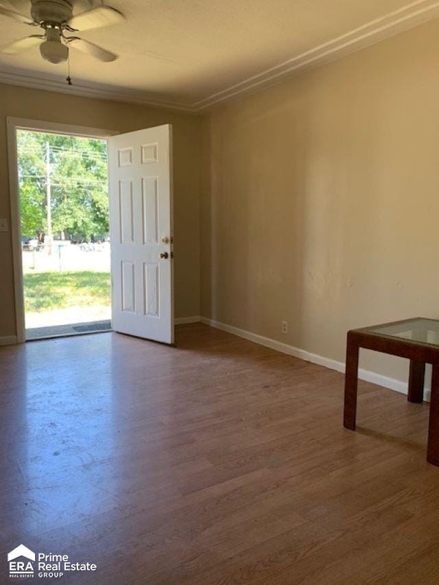 empty room featuring ceiling fan, wood-type flooring, and crown molding