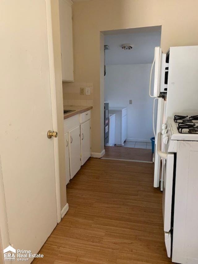 kitchen featuring white gas range, light wood-type flooring, and white cabinetry