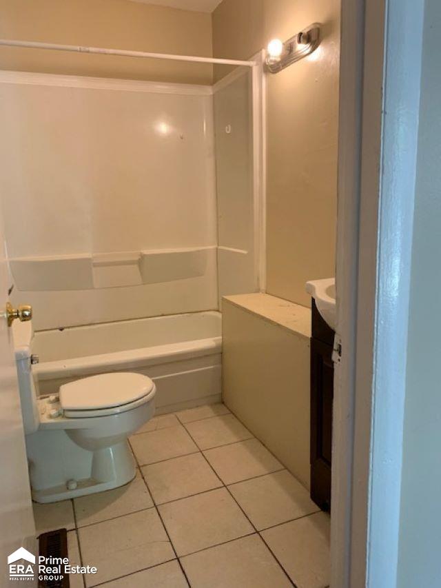 full bathroom with tile patterned floors, vanity, toilet, and washtub / shower combination