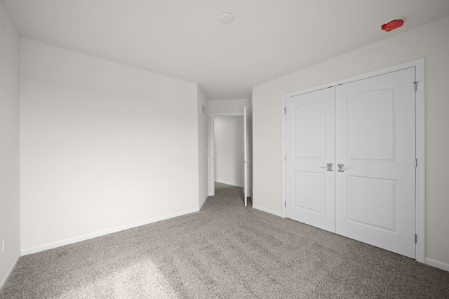 unfurnished bedroom with carpet flooring, baseboards, and a closet