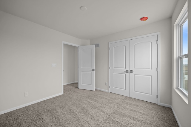 unfurnished bedroom with visible vents, baseboards, a closet, and carpet flooring