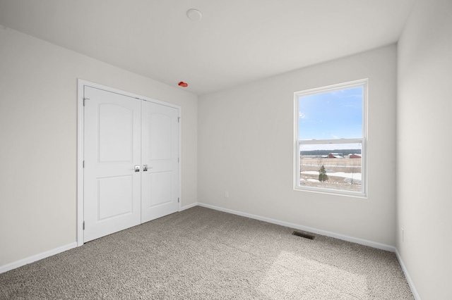 unfurnished bedroom with visible vents, baseboards, a closet, and carpet flooring