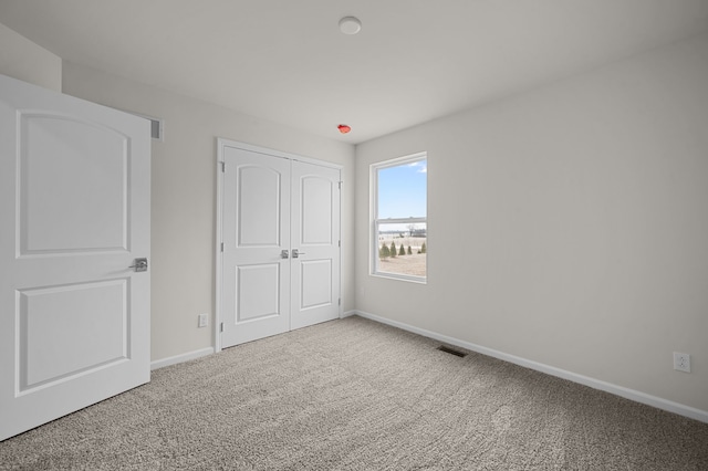 unfurnished bedroom with carpet, visible vents, a closet, and baseboards