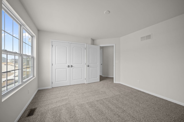 unfurnished bedroom with a closet, visible vents, baseboards, and carpet floors