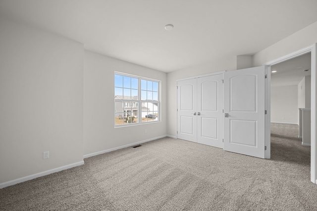 unfurnished bedroom featuring carpet flooring, baseboards, visible vents, and a closet