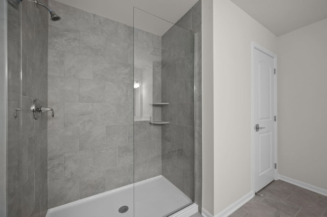 full bath with a tile shower and baseboards