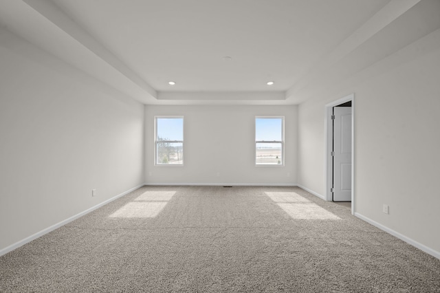 unfurnished room with light colored carpet, a tray ceiling, recessed lighting, and baseboards