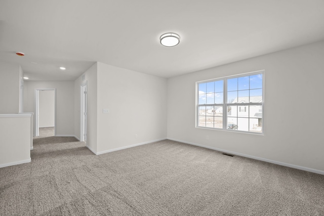 carpeted spare room with visible vents and baseboards