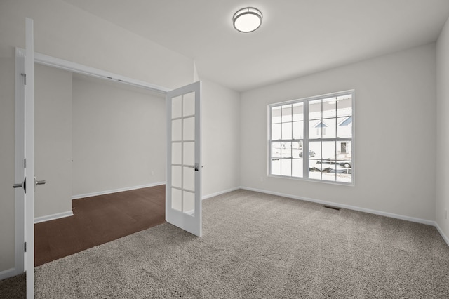 unfurnished room with visible vents, french doors, carpet, and baseboards