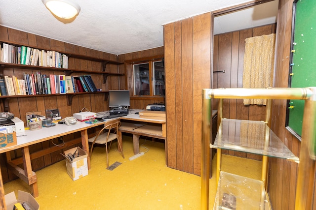 office with concrete floors, a textured ceiling, and wooden walls