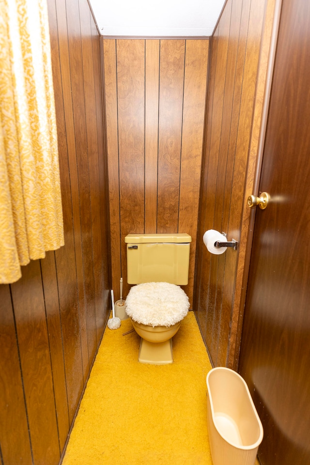 bathroom featuring wood walls and toilet