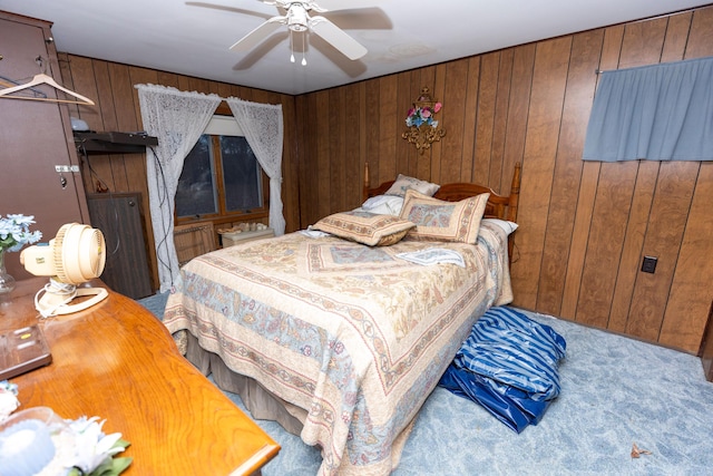bedroom featuring carpet floors, wood walls, and a ceiling fan
