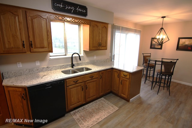 kitchen featuring sink, hanging light fixtures, black dishwasher, light hardwood / wood-style floors, and a chandelier