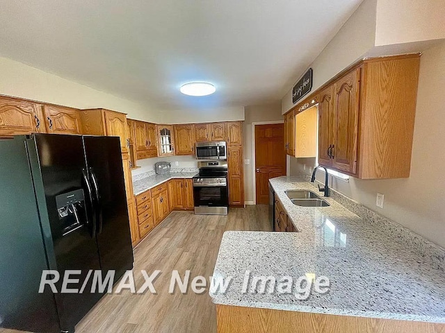 kitchen featuring light hardwood / wood-style floors, sink, light stone countertops, and stainless steel appliances