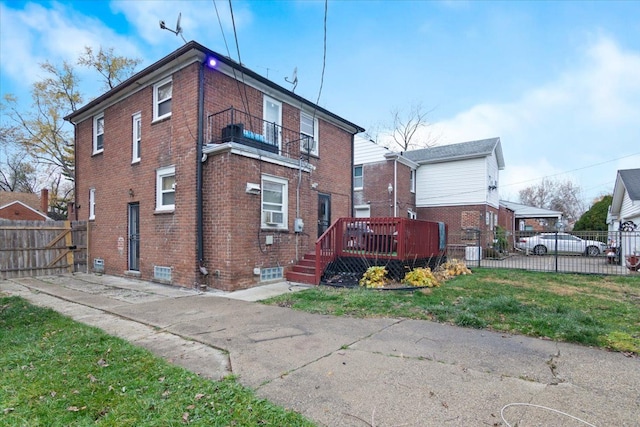 rear view of house with a lawn, a balcony, and a wooden deck