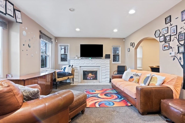 carpeted living room featuring a stone fireplace