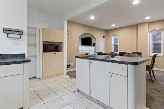 kitchen with light carpet, light brown cabinets, a center island, and black appliances