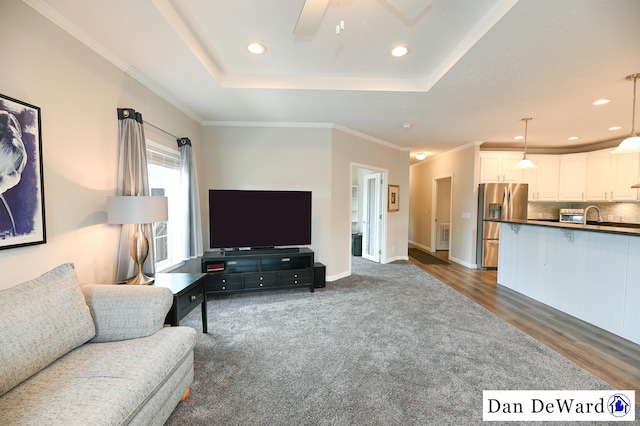 living room featuring ceiling fan, ornamental molding, dark hardwood / wood-style flooring, and a tray ceiling