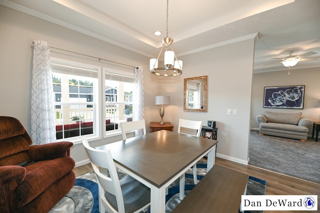 dining area featuring ceiling fan, ornamental molding, a raised ceiling, and hardwood / wood-style floors