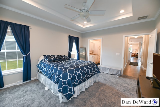 carpeted bedroom featuring ceiling fan, ensuite bathroom, a tray ceiling, and ornamental molding