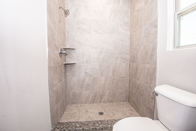 bathroom featuring tiled shower and toilet