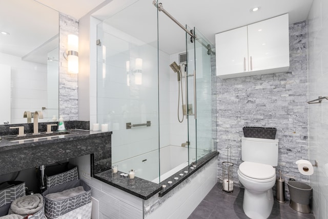 bathroom featuring toilet, tiled shower / bath combo, tile walls, tile patterned flooring, and vanity