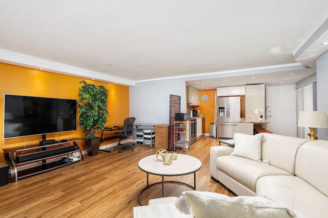 living room with recessed lighting, light wood-style flooring, and a textured ceiling