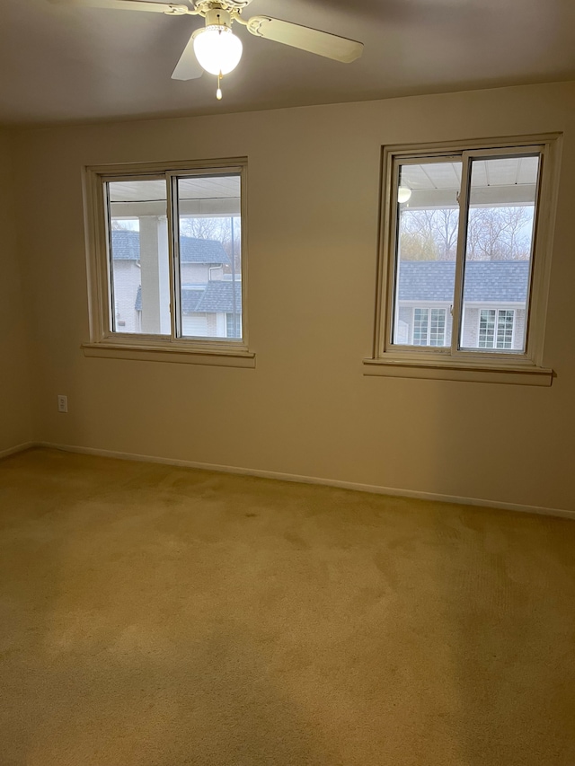 carpeted spare room featuring ceiling fan and a healthy amount of sunlight