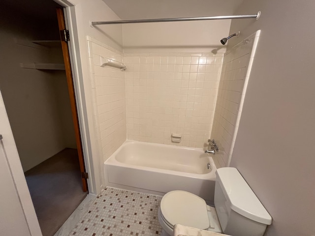 bathroom featuring tile patterned flooring, toilet, and tiled shower / bath