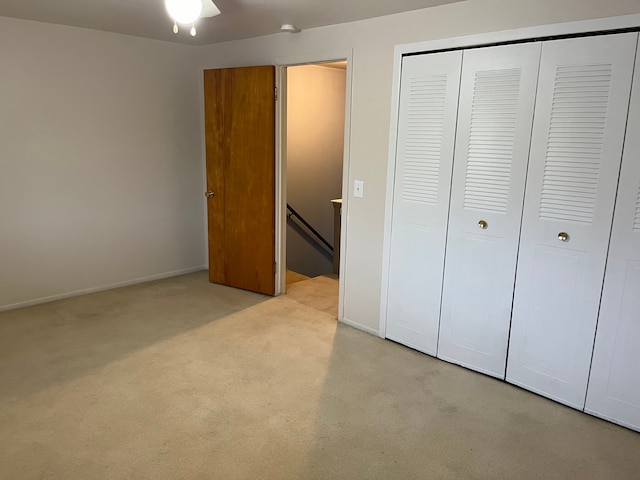 unfurnished bedroom featuring ceiling fan, light colored carpet, and a closet