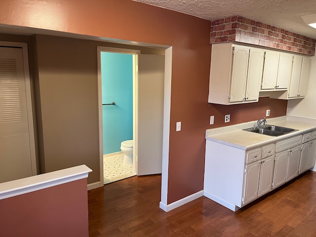 kitchen featuring white cabinets, a textured ceiling, sink, and dark wood-type flooring