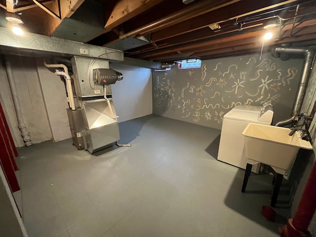 basement featuring washing machine and dryer, heating unit, and sink