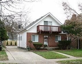 view of front facade with a balcony and a front yard