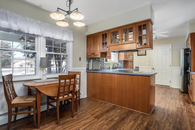 kitchen featuring kitchen peninsula, decorative backsplash, ceiling fan, and dark wood-type flooring