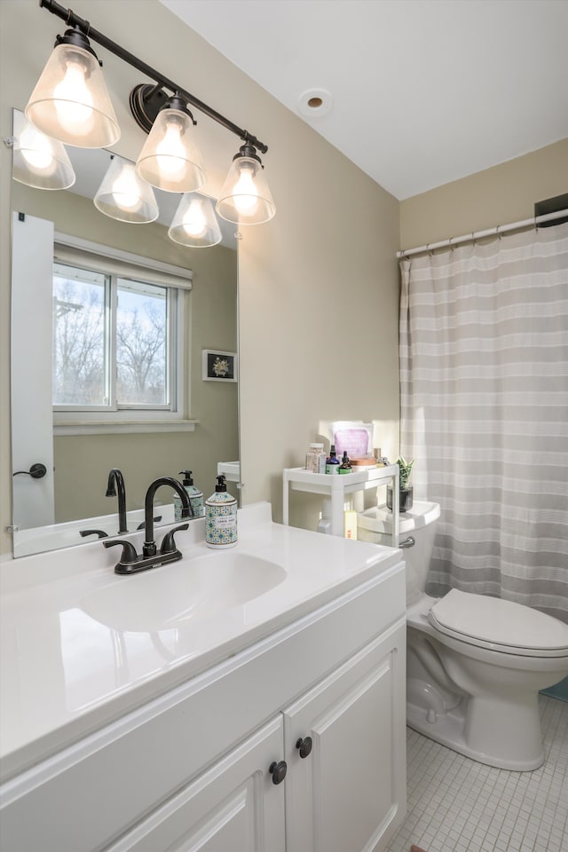 bathroom with toilet, vanity, and tile patterned floors