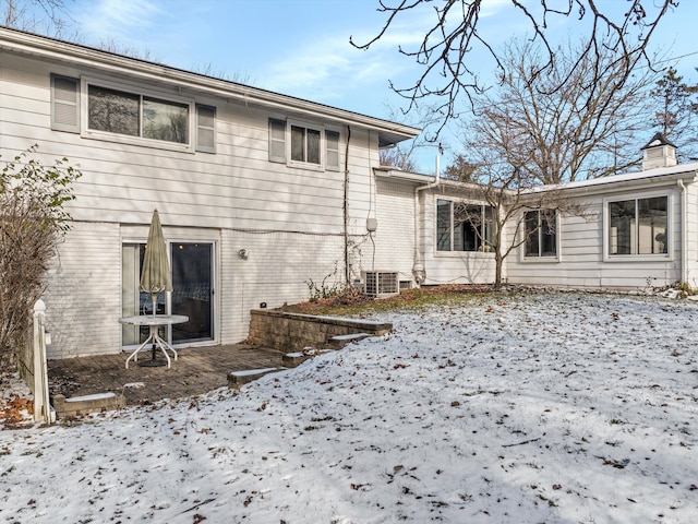 snow covered back of property featuring central AC